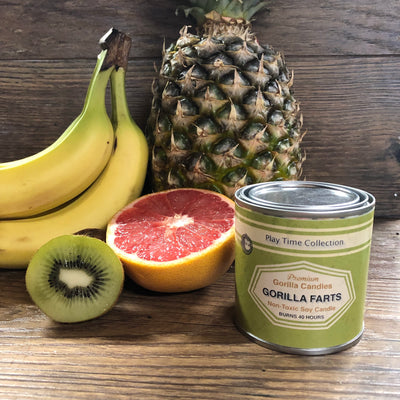 Gorilla Farts candle surrounded by kiwi, grapefruit, bananas, and a pineapple.